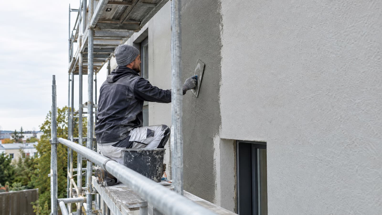 Façadier ravalant une façade sur échafaudage, assurance décennale à Lille