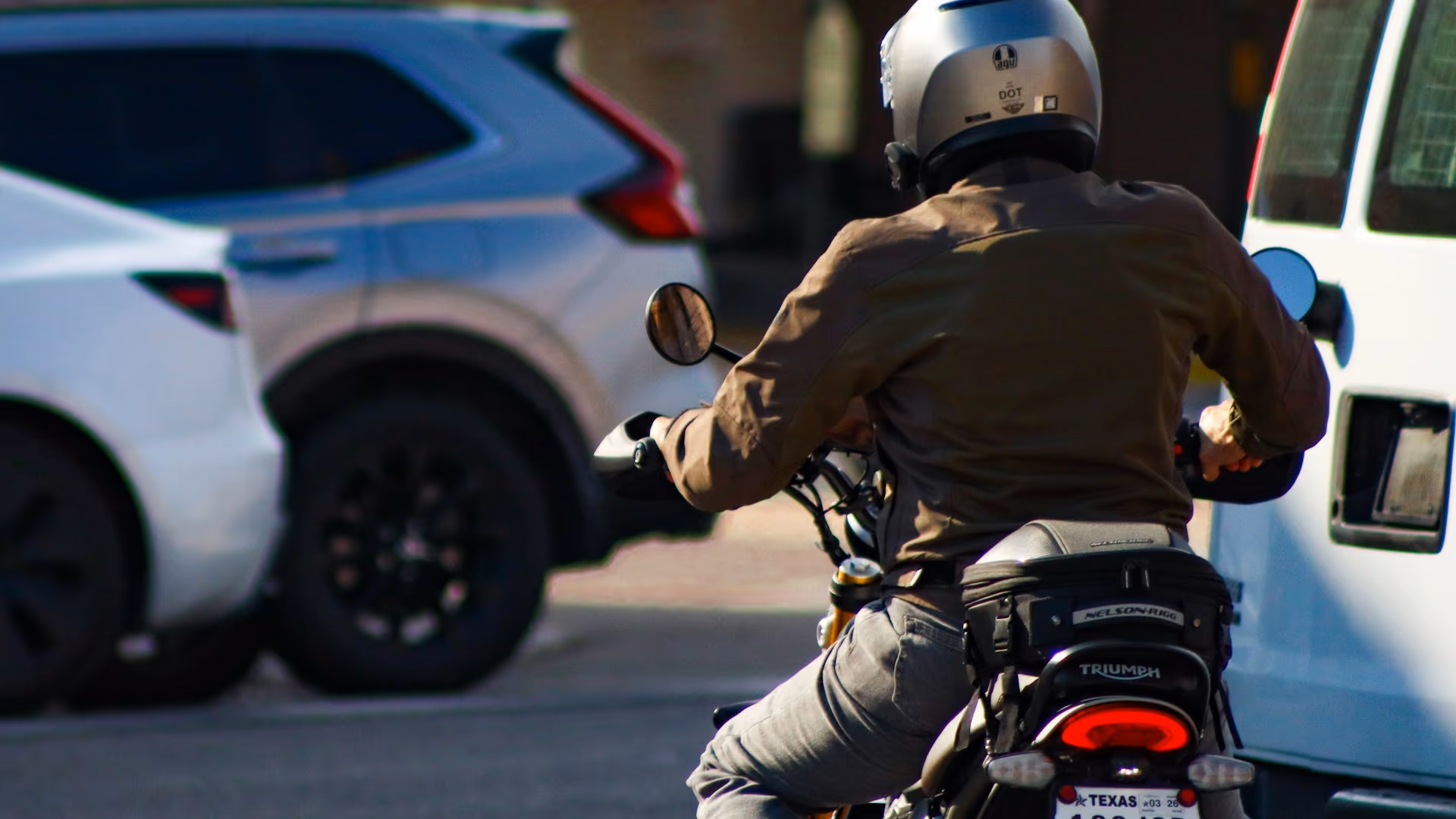 Motard avec casque entre voitures urbaines — assurance moto AGI